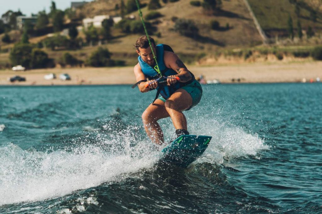 young man doing wakeboarding in a lake whit mountains also doing jumpsyoung man doing wakeboarding in a lake whit mountains also doing jumps
